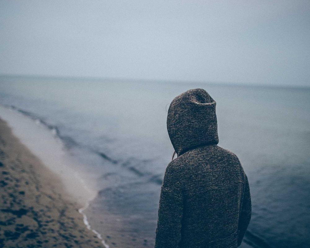 Person reflecting quietly by the sea, representing long-term life insurance planning
